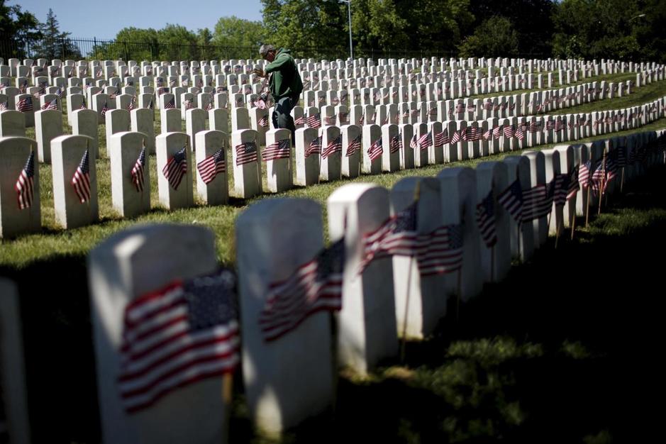 worker-places-u-s-flags-at-graves-at-cypress-hills-national-cemetery-in-brooklyn-new-york